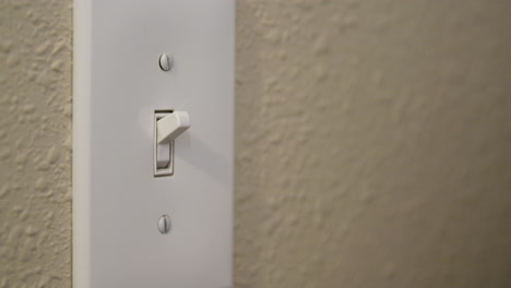 man's hand turns light switch off then on