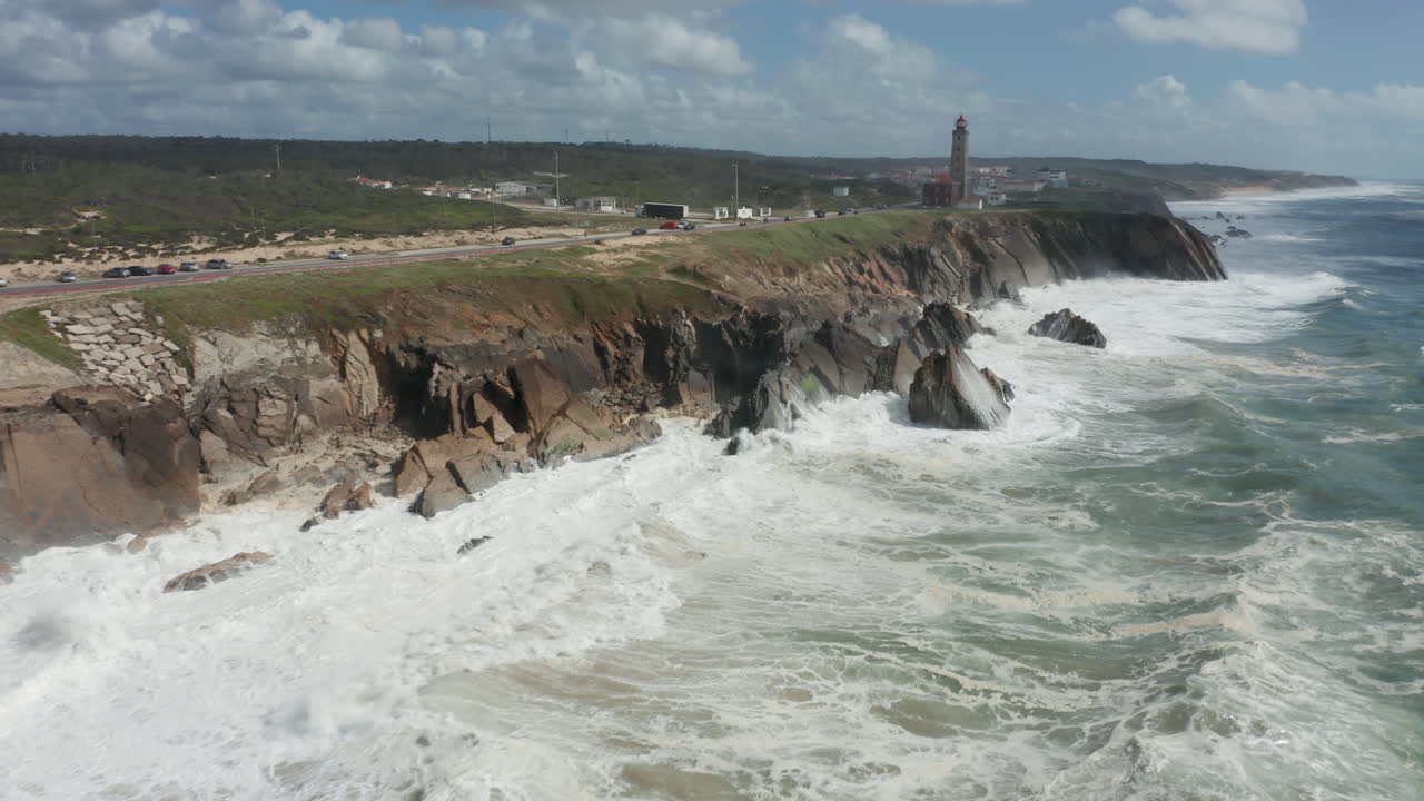 Aerial of rocky cliffs with big waves coming from the sea hitting rocks