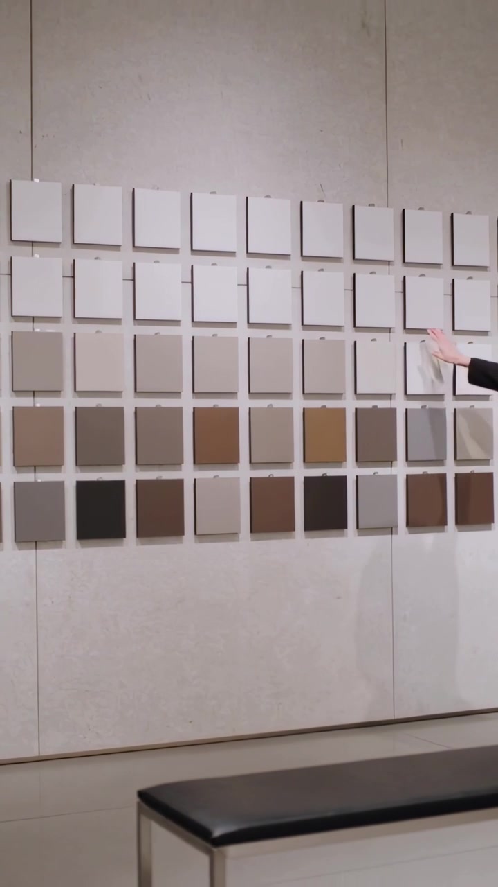 Vídeo vertical: Mulher de terno preto estendendo a mão, deslizando azulejos no estúdio para inspecionar e depois recuando