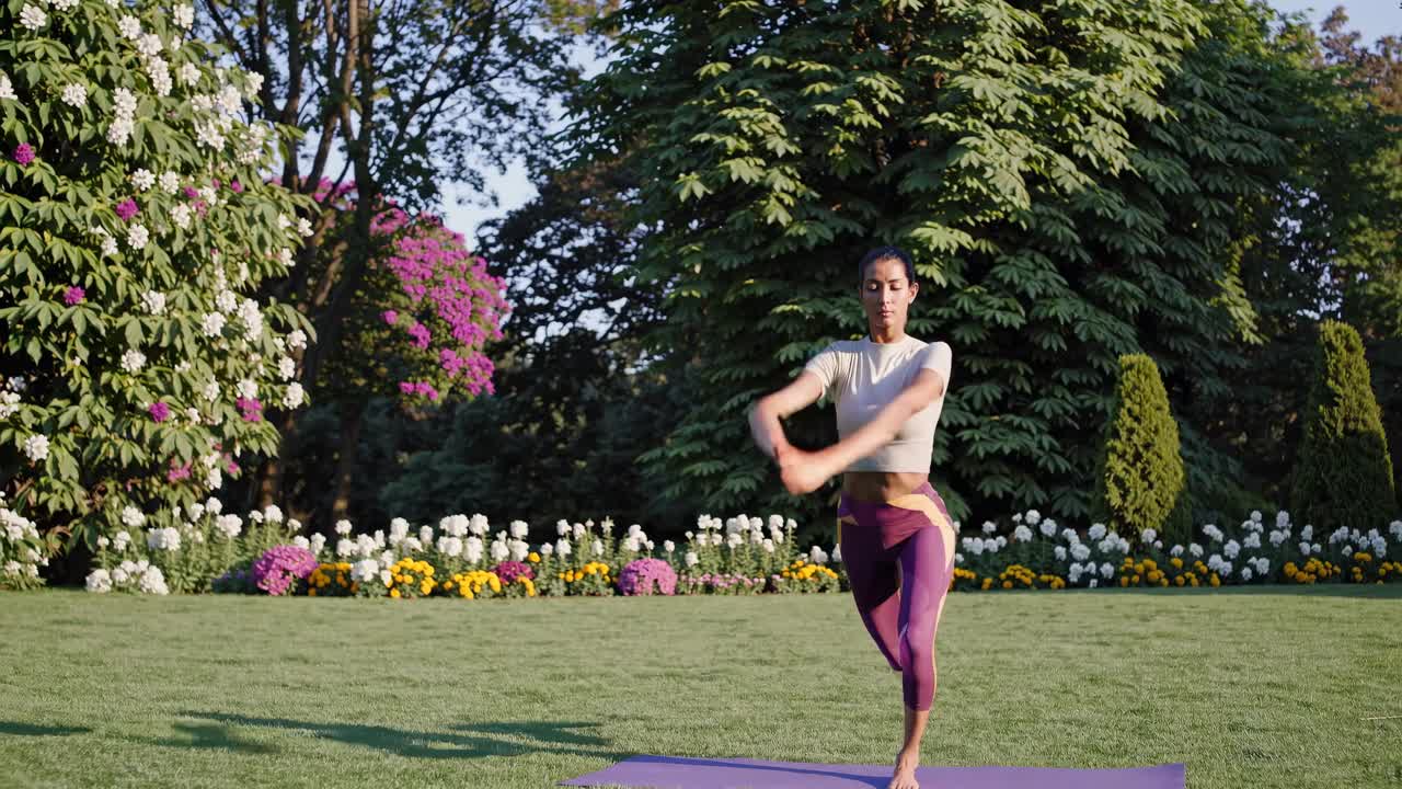 A woman practices yoga in a garden, captured in a wide-angle shot