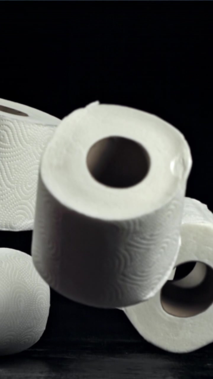 White Toilet Paper Rolls Falling in Slow Motion on a Dark Surface