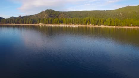 An-aerial-shot-over-Lake-Tahoe-approaching-the-shore-and-over-old-pilings-in-water