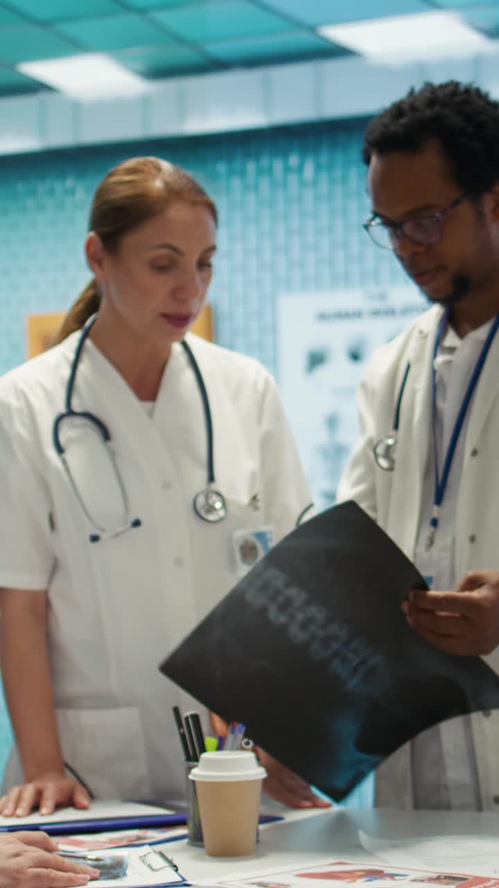 Video verticale: Specialisti discutono i risultati dei raggi X e la strategia di cura del paziente in uno studio medico