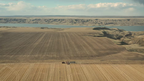 Tractor-Sembrando-Nueva-Cosecha-En-Suelo-Cultivable-Con-Lago-Diefenbaker-Detrás