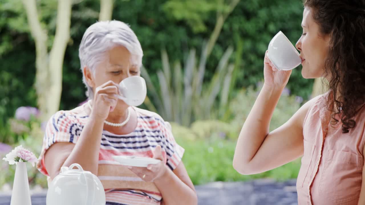 어머니와 딸이 정원에서 커피를 마시고 있습니다. 4k 4k
