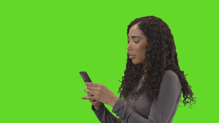 Ripresa di profilo di donna che invia messaggi sul cellulare su sfondo verde