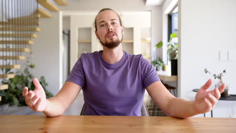 a young caucasian man gestures while speaking on a video call at home