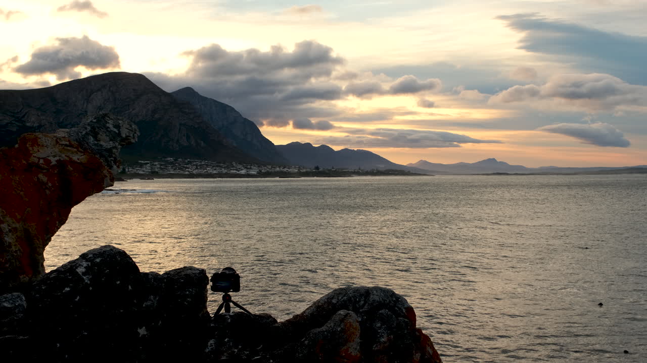 Camera on mini tripod on coastal cliff in Hermanus taking footage of sunrise