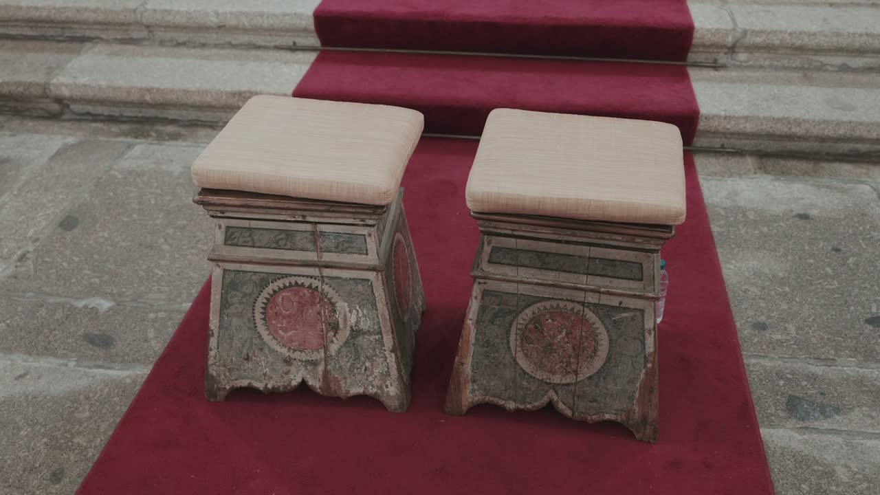 Vintage wooden stools with ornate carvings placed before altar