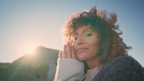 curly brunette enjoying sunset at wild nature portrait. happy lady warming hands