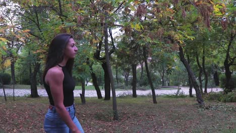 young beautiful model walking in a park with trees with green leaves