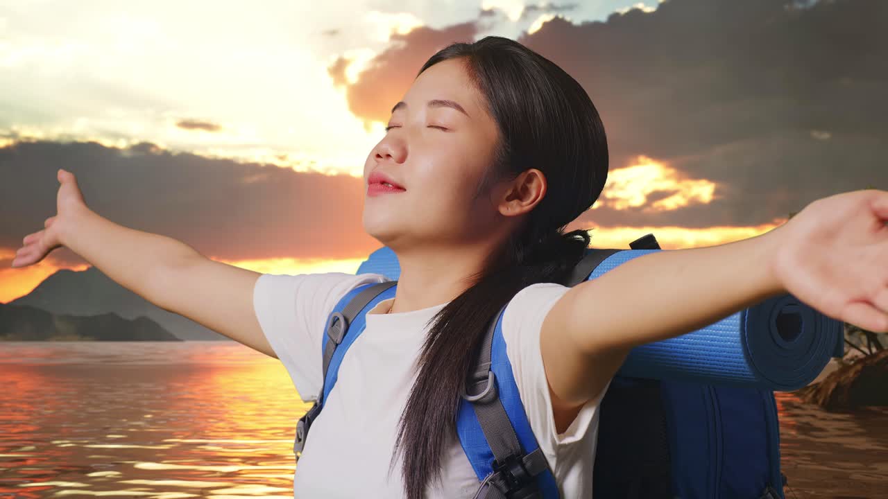 Close Up Side View Of Asian Female Hiker With Mountaineering Backpack Spreading Arms Enjoy Looking The View Around At A Lake