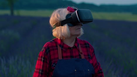 Senior-grandmother-farmer-in-virtual-reality-helmet-managing-quality-in-field-of-lavender-flowers