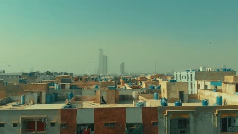 aerial over rooftops with view of bahria icon tower in the distance in karachi. pedestal up