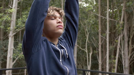 young man in blue hoodie practicing mindfulness outdoors in peaceful forest