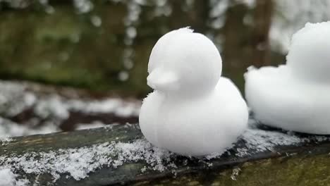 Sammlung-Geformter-Schneeenten-Als-Dekoration,-Die-In-Einer-Reihe-Auf-Einem-Holztor-Im-Winterwald-Sitzen