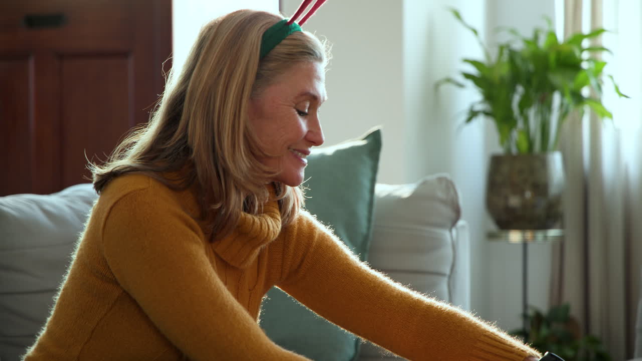 At Christmas, Smiling senior woman wearing reindeer headband enjoying holiday at home
