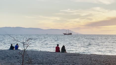 Parejas-Sentadas-En-La-Playa-En-México-Viendo-Barcos-Al-Atardecer