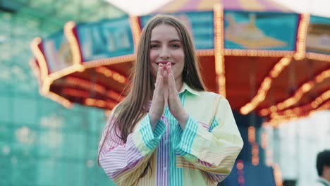 beautiful young caucasian girl clapping outside in a amusement park while wearing vibrating coulours