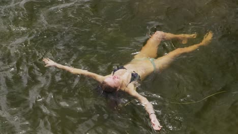 caucasian woman having a good time on a trip to the mountains, wearing bathing suit and floating on