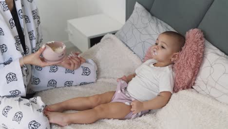 little-girl,-an-infant,-being-fed-by-her-mother's-hands-with-porridge-from-a-spoon