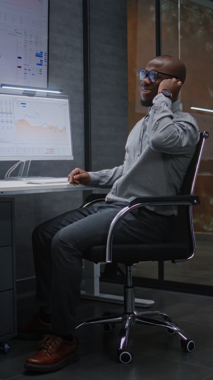 Advanced Trading Office: Excited Financial Analyst Having Phone Call, Celebrating Profitable Investments. African American Businessman Happy about Successful Financial Deal or Contract. Vertical Shot.