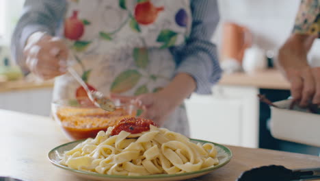 adding homemade tomato sauce to freshly cooked pasta on plate