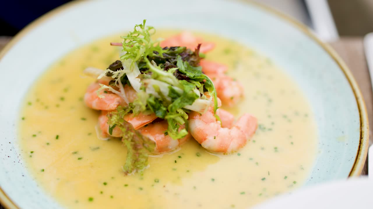 Hand lifts shrimp, greens, and grits with spoon from gourmet plate in bright natural light