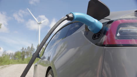 slider - a generic electric vehicle is plugged in, wind turbine behind