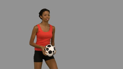 mujer haciendo malabarismos con un fútbol en la pantalla gris