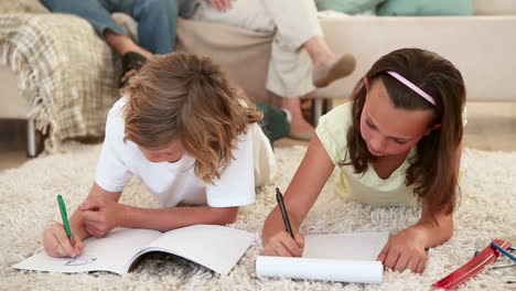 siblings doing their homework on the living room floor with their parents behind them