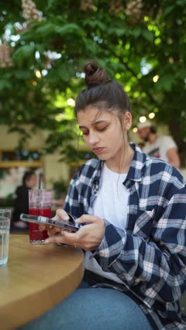joven usando el teléfono en un café al aire libre