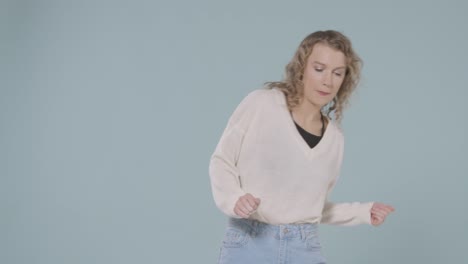 Studio-Shot-Of-Young-Woman-Having-Fun-Dancing-Against-Blue-Background