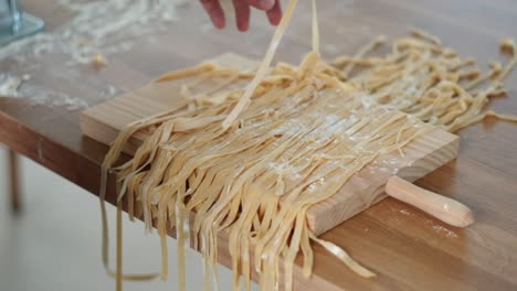 cinematic delight: close-up of artisan baker chef preventing tagliatelle from sticking - homemade egg pasta