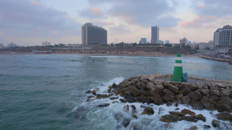 el rompeolas de la marina de tel aviv junto a los surfistas en la playa de hilton - empujar en la toma