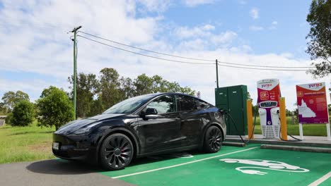 black electric car charging at a rural station