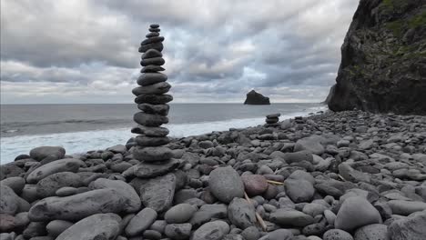 Steinturm-An-Einem-Steinstrand-Mit-Dem-Strand-Im-Hintergrund-An-Einem-Bewölkten-Tag-Und-Den-Wellen,-Die-Sich-Langsam-Hineinbewegen