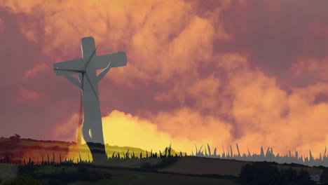 vibrant sunset sky with silhouette of cross over grassy landscape