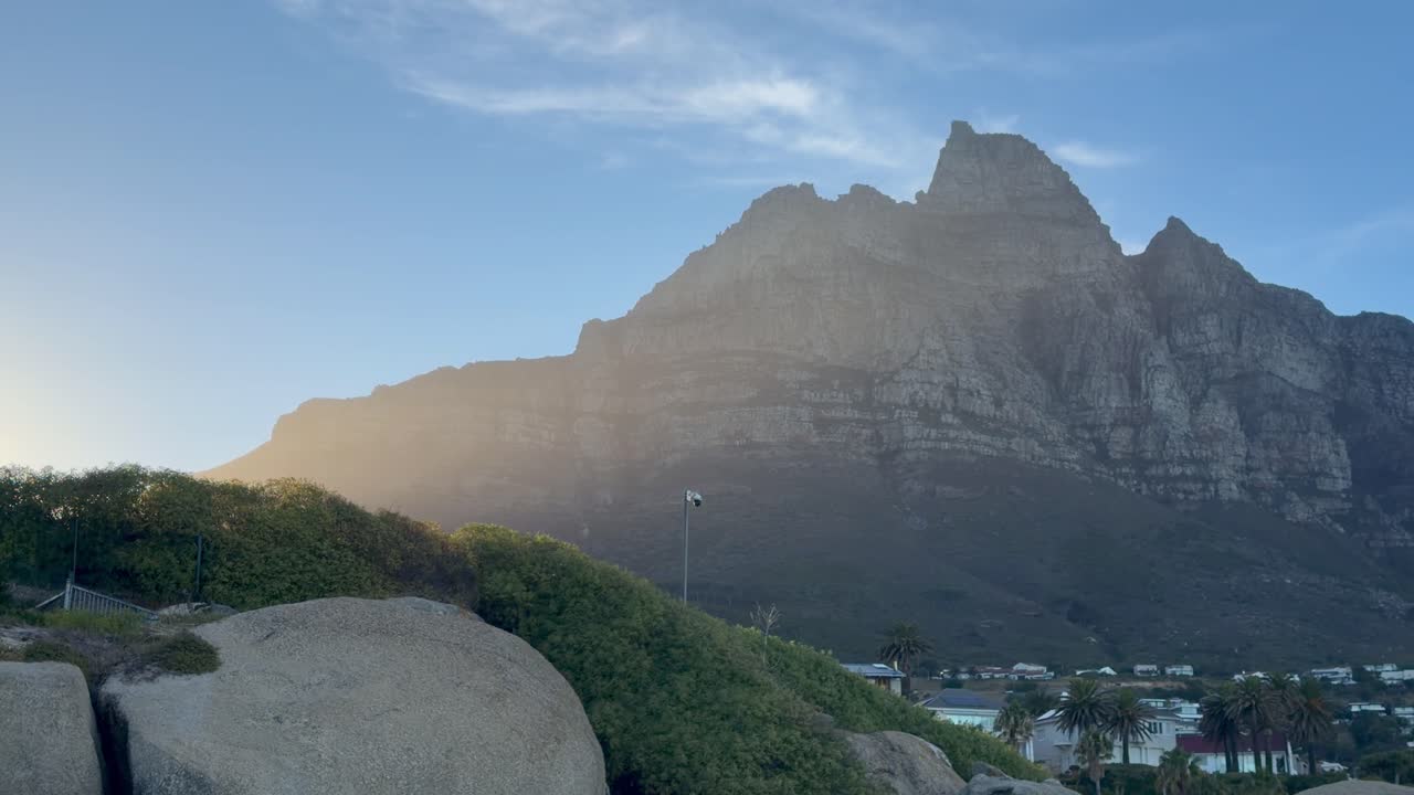 Una vista panoramica di Camps Bay con la Table Mountain e la catena montuosa dei 12 Apostoli sullo sfondo, subito dopo l'alba. Camps Bay, Città del Capo, Sudafrica.