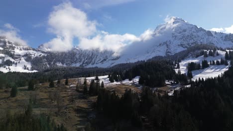 Aerial-drone-shot-flying-over-partly-snow-covered-mountain-slope-on-a-cold-winter-day