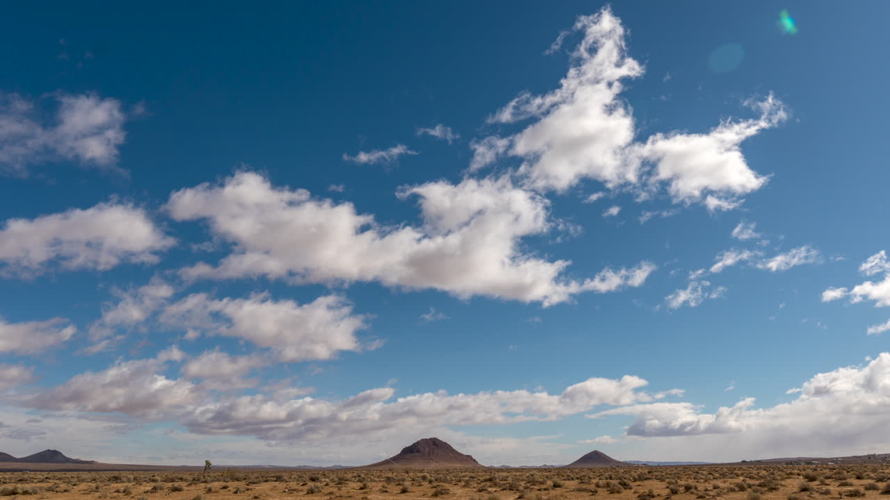 las nubes ruedan por el cielo sobre el terreno accidentado del desierto de mojave - lapso de tiempo estático de gran angular