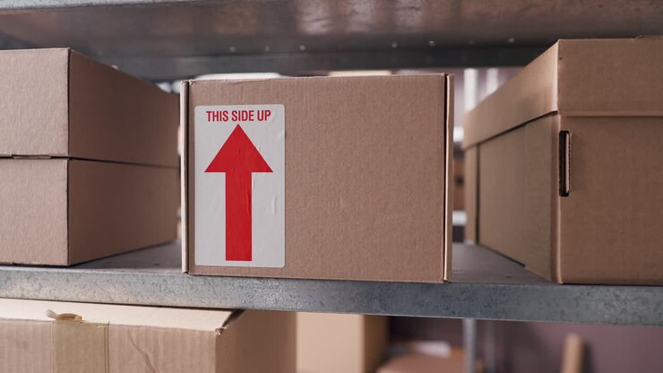Cardboard Box with 'This Side Up' Label on Warehouse Shelf