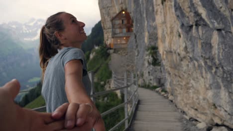 pov of couple holding hands, man leading friend to mountain ridge.