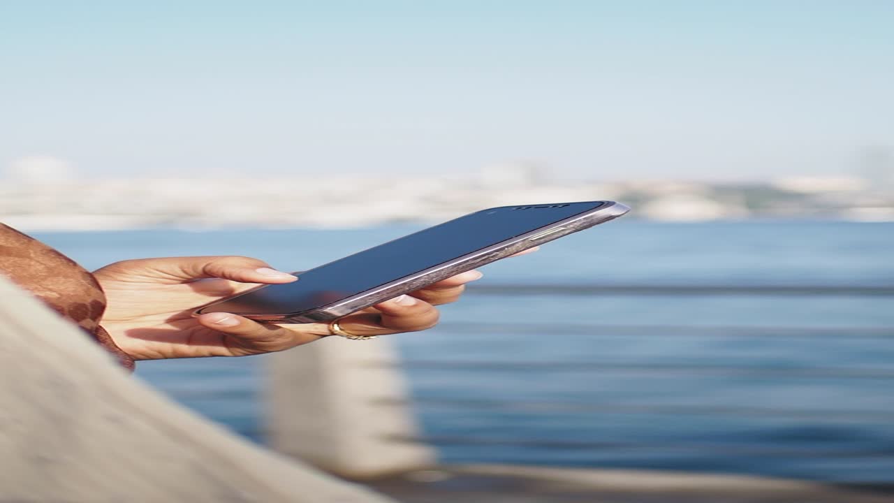 una mujer usando su teléfono junto al agua