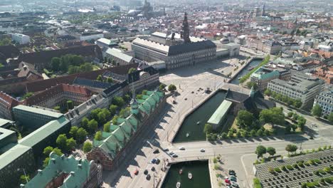 Aerial-flyover-Christiansborg-Castle-and-Borsen-Stock-Exchange,-Copenhagen,-Denmark