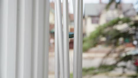 closeup of a wind chime moving in the wind with a blurred background of houses and trees on a quiet street