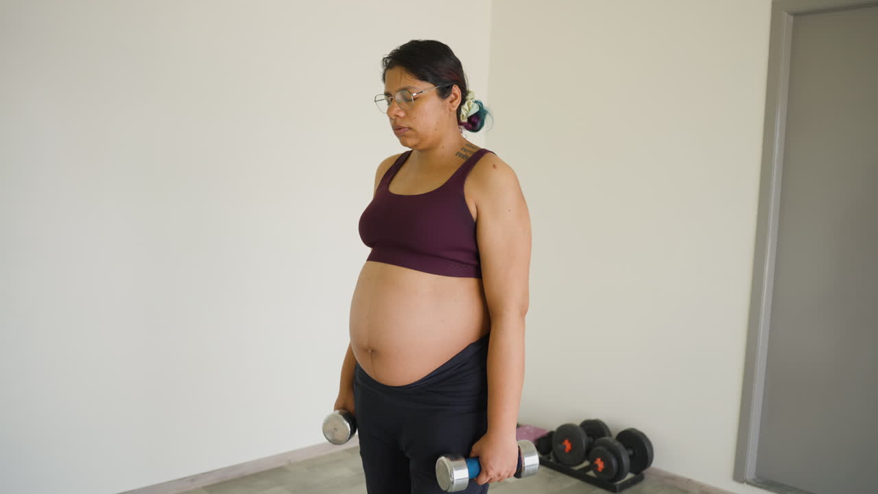 Donna indiana incinta attiva che esercita le spalle durante il terzo trimestre di gravidanza