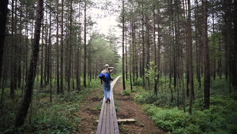 Folgeaufnahme-Eines-Jungen-Mannes-Mit-Kamera,-Der-Auf-Brettern-Durch-Den-Wald-Geht