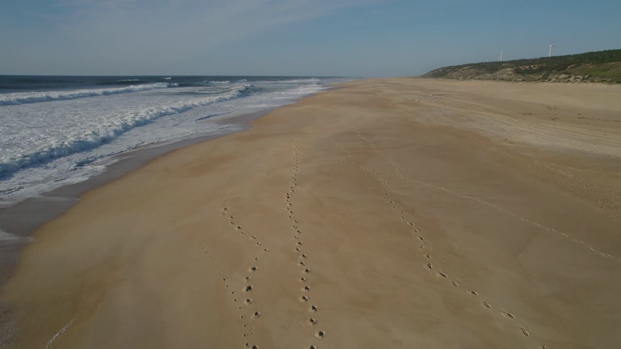 Spiaggia deserta di Nazaré con onde leggere che si infrangono placidamente sulla riva sotto un cielo invernale