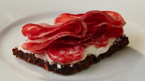 hand placing cured meat on a sandwich